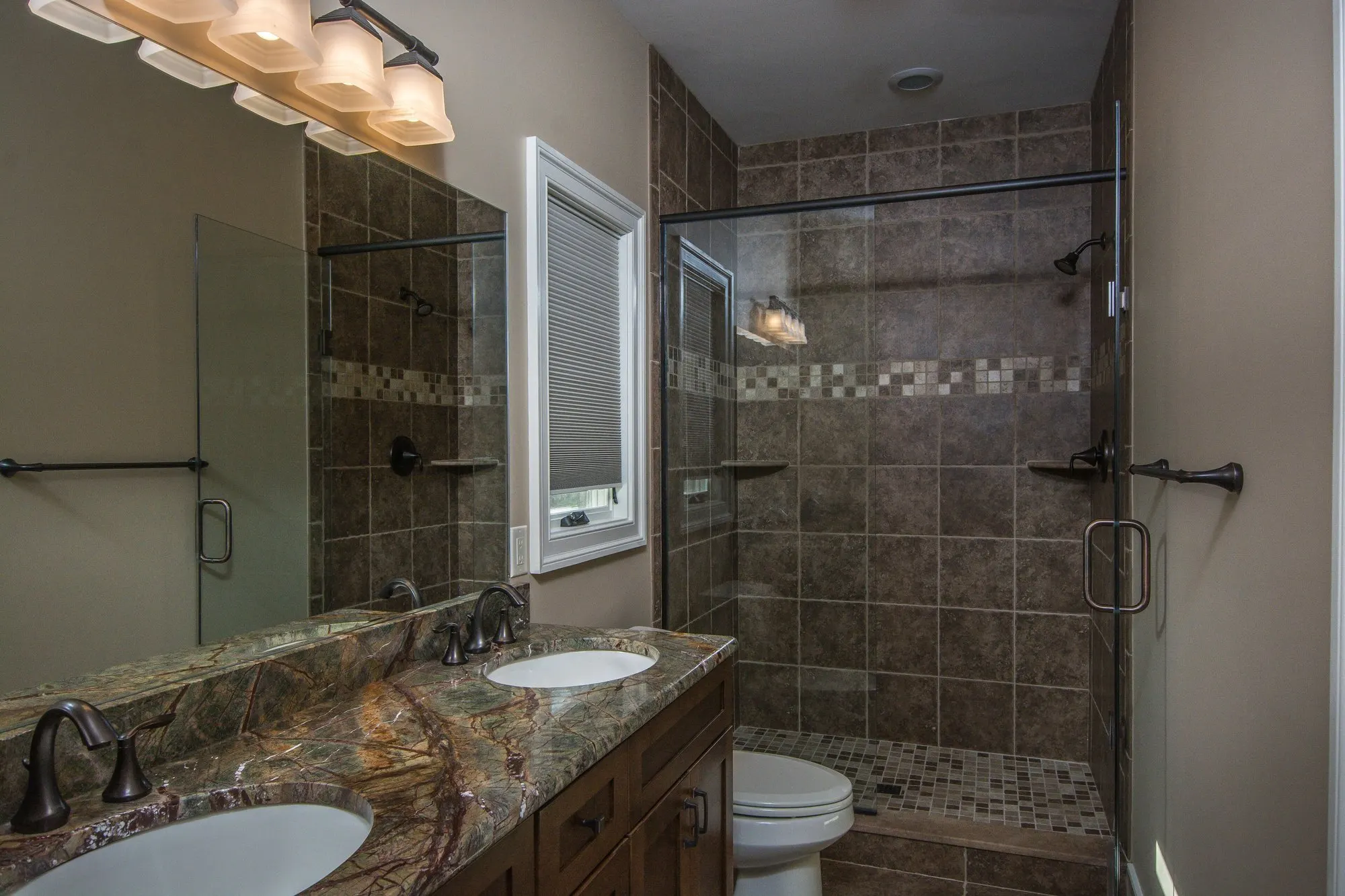 Main level full bath with dual sinks and a glass shower