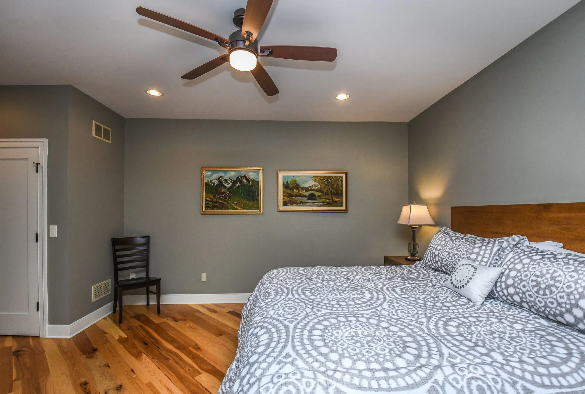Main level bedroom with a reading chair beside the bed